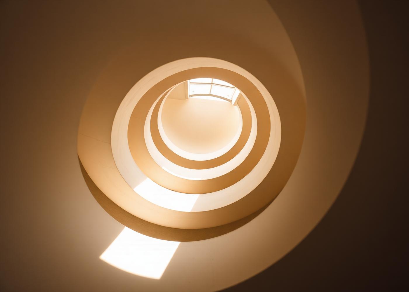 A spiral staircase seen from below, lit from above